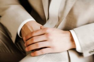 Ein Mann im Hochzeitsanzug hält bequem seine Hände.
